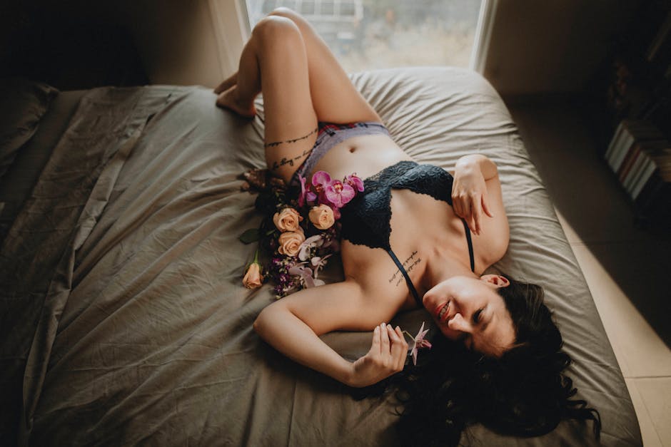 Boudoir portrait with flowers on a bed in soft natural light